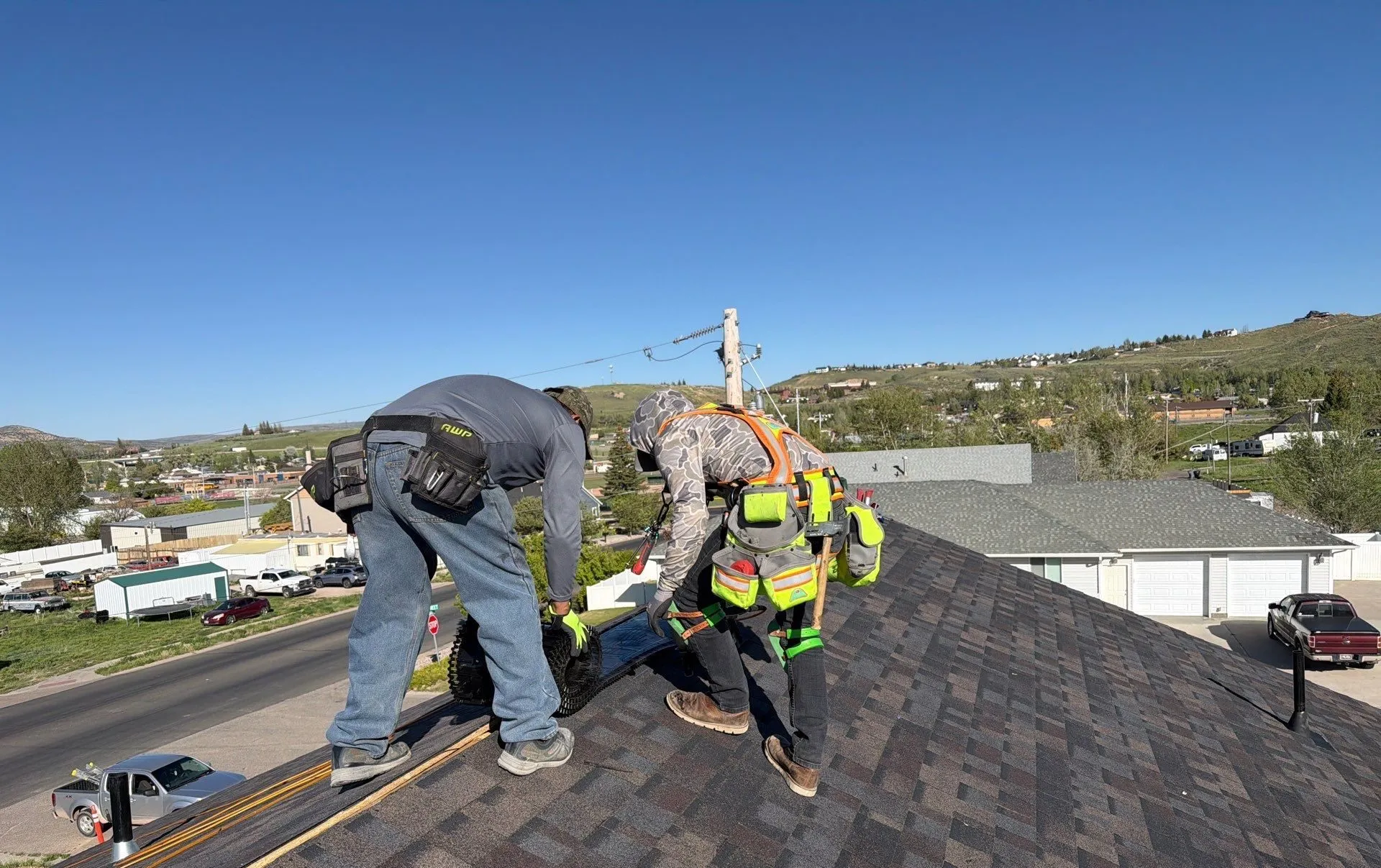 The Gregco crew installing a new roof, with a roofer in a safety harness and hi-vis vest
